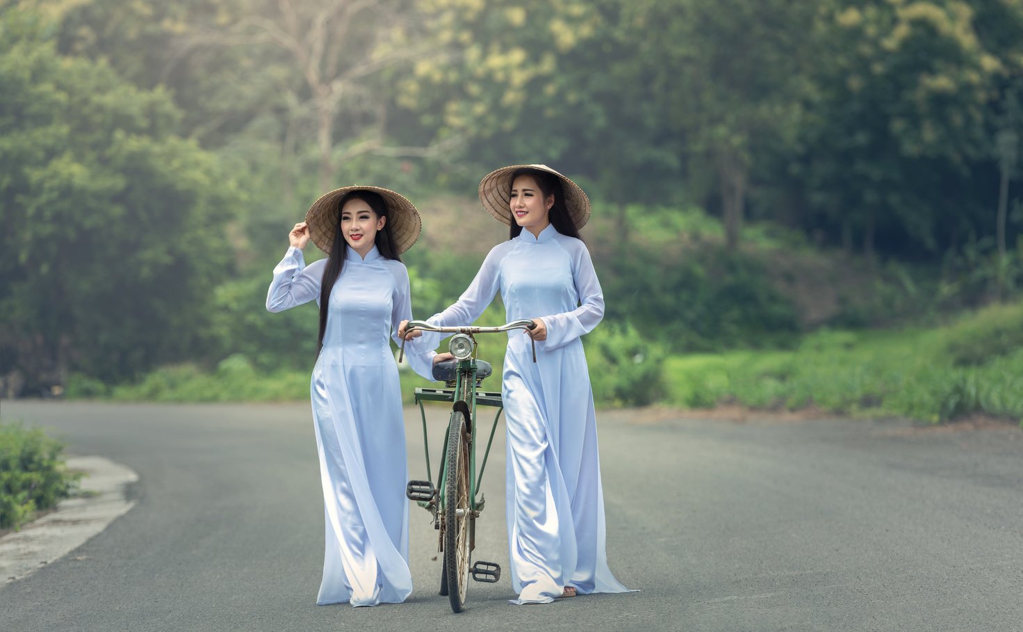 Women in Vietnamese Attire Walking with a Bicycle.